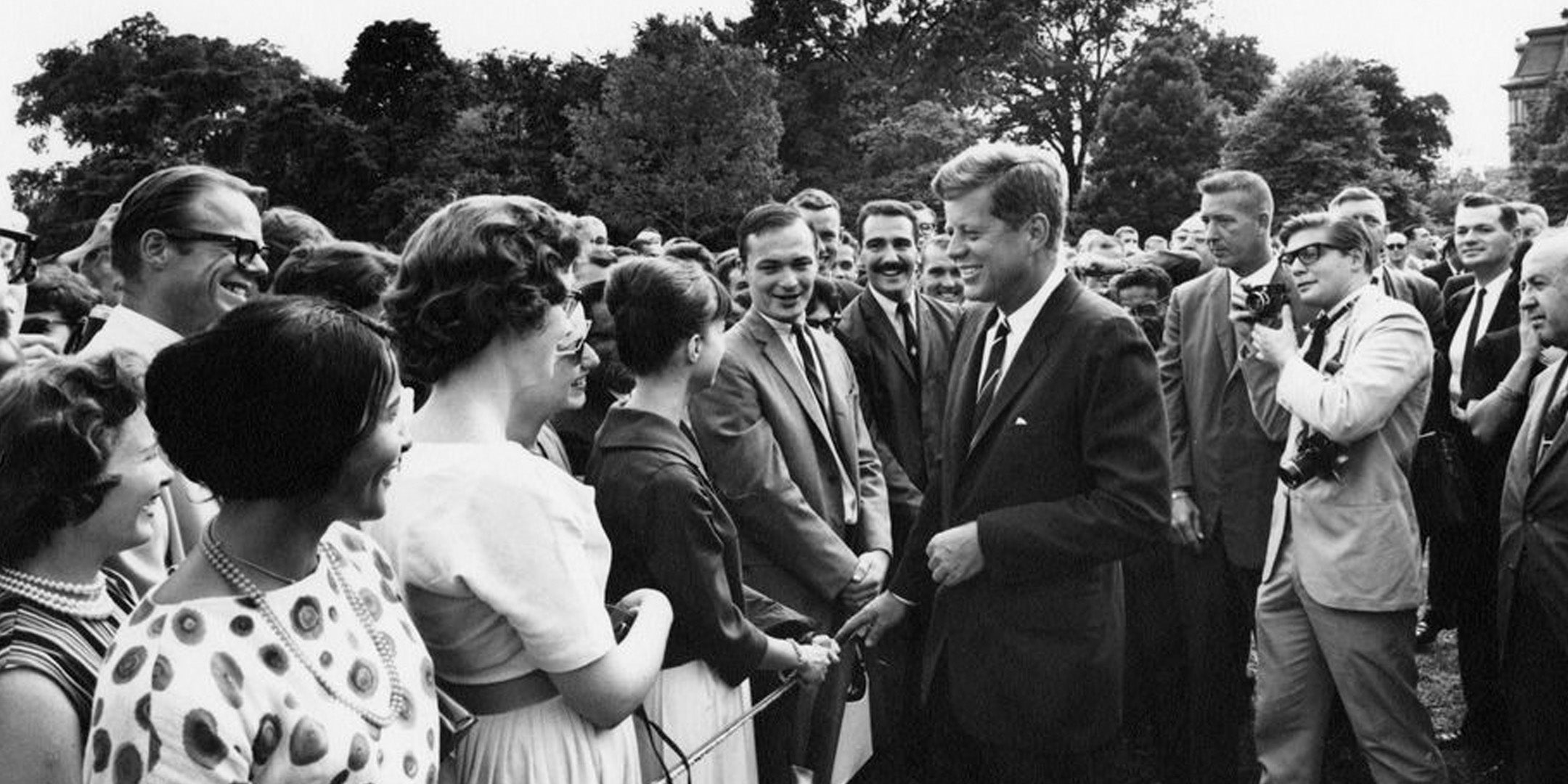 JFK greeting people in a crowd and smiling 